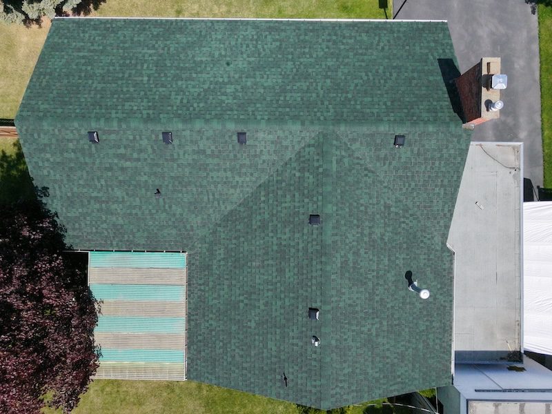 Top-down aerial of large green shingle roof showing complete NuRoof treatment coverage