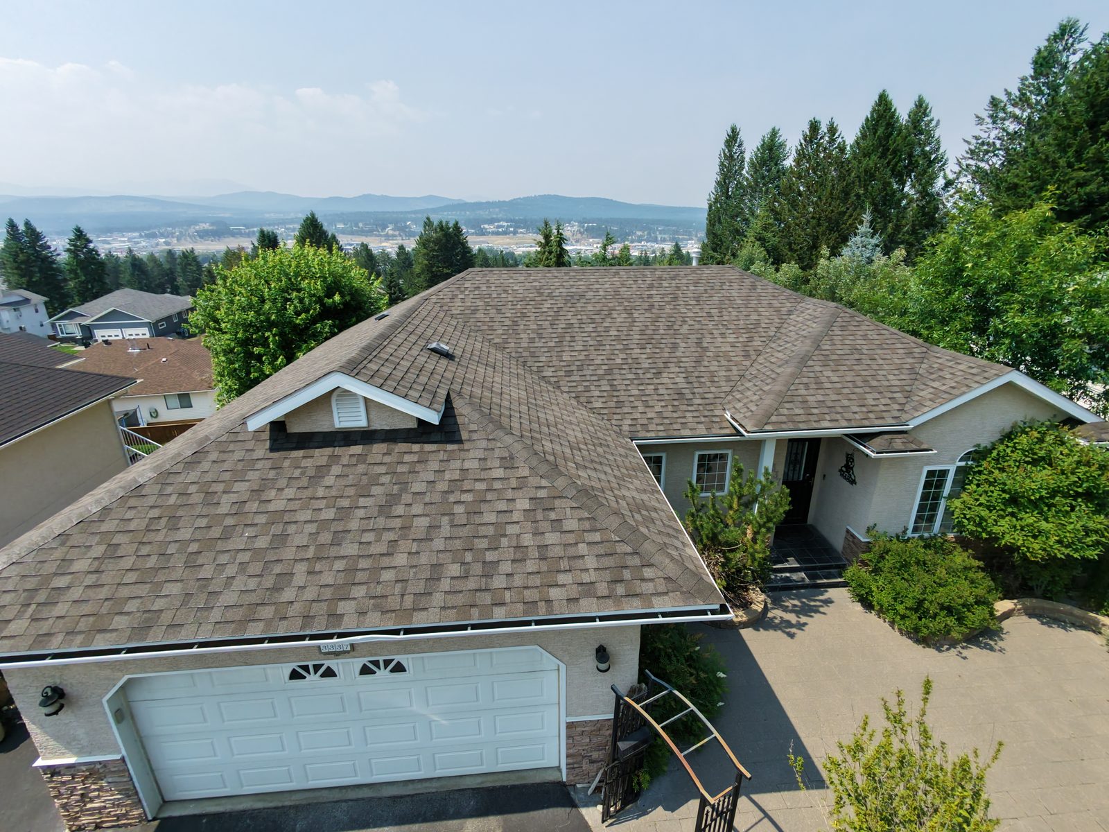 Aerial view of a tan shingle roof treated with NuRoof overlooking the Cranbrook valley