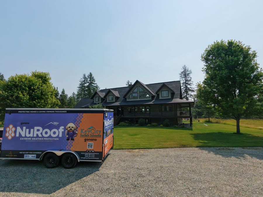 Key City Surface Solutions NuRoof trailer parked in front of a large East Kootenay home
